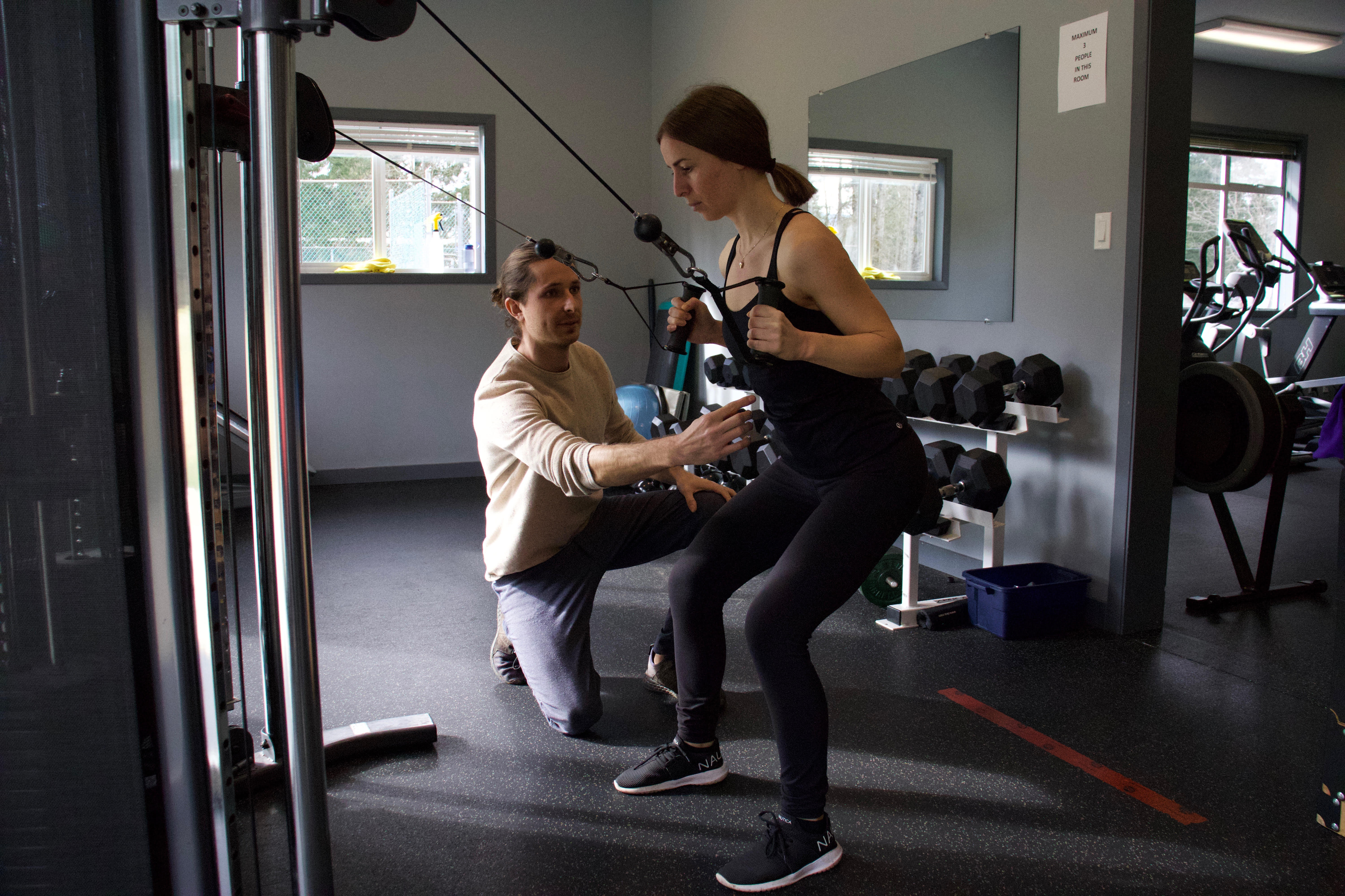 Woman working closely with Kinesiologist in Black Creek BC, to improve her strength using gym exercises.